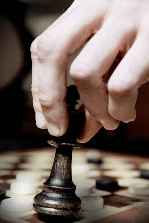 Chess board with a piece in a person’s hand