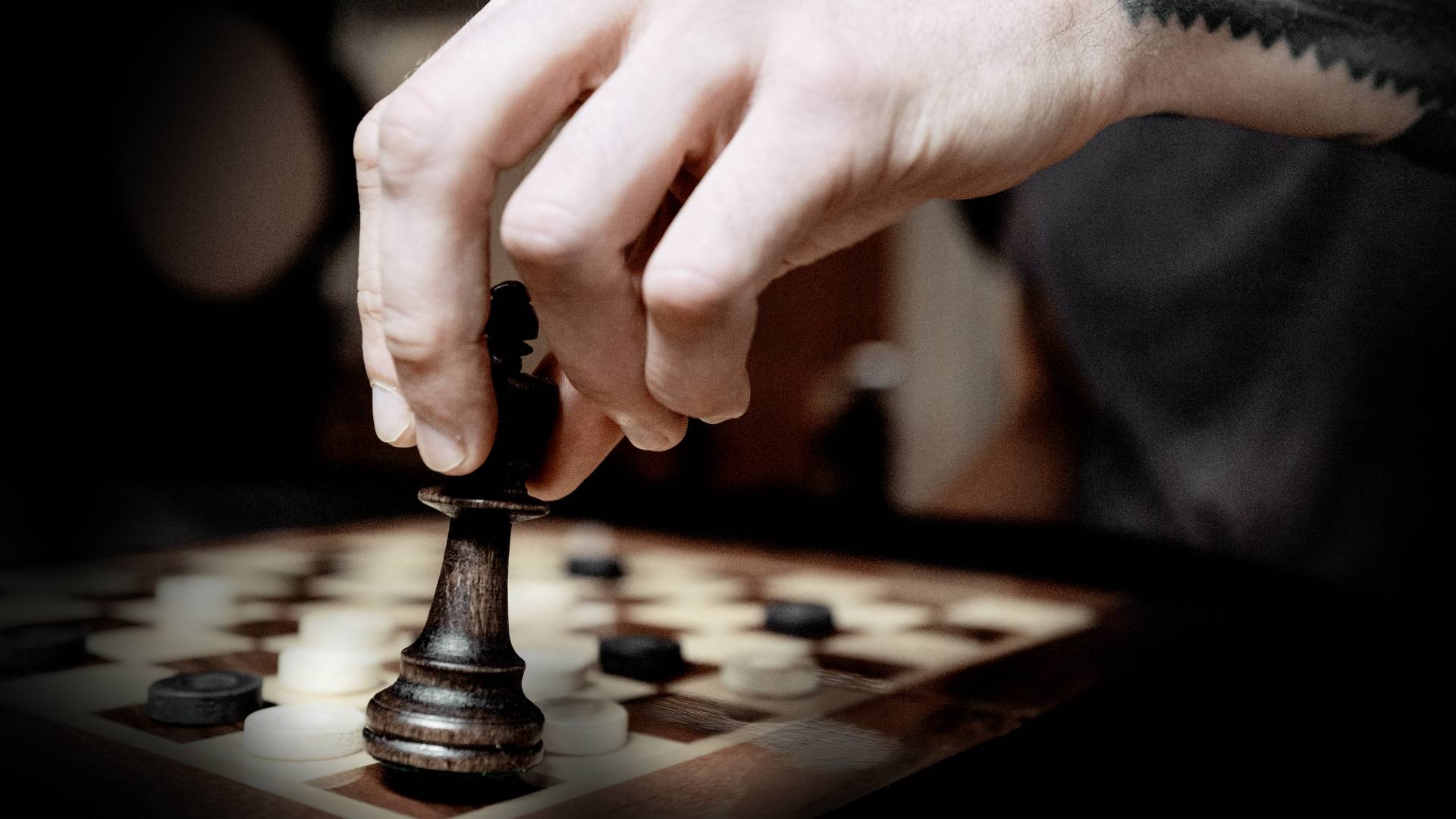 Chess board with a piece in a person’s hand
