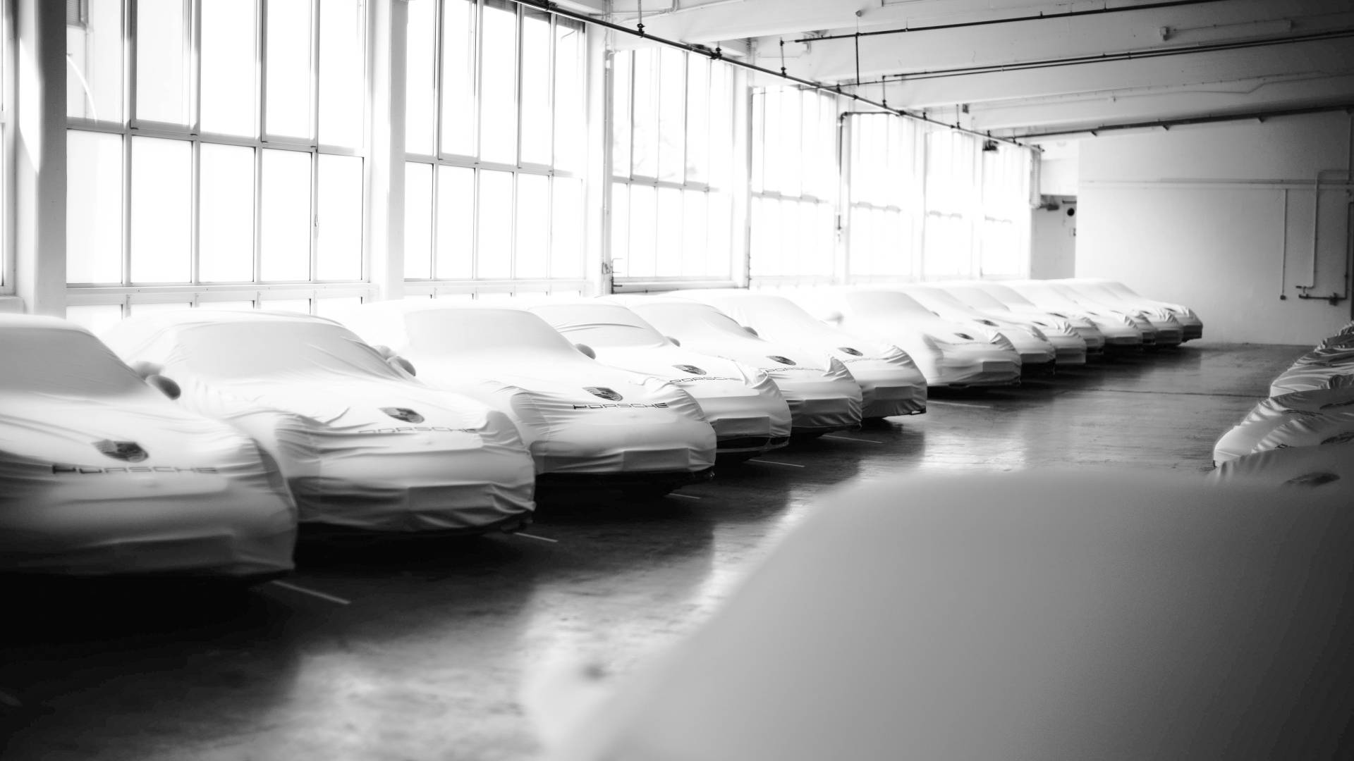 Mehrere bedeckte Porsche in einer Halle 