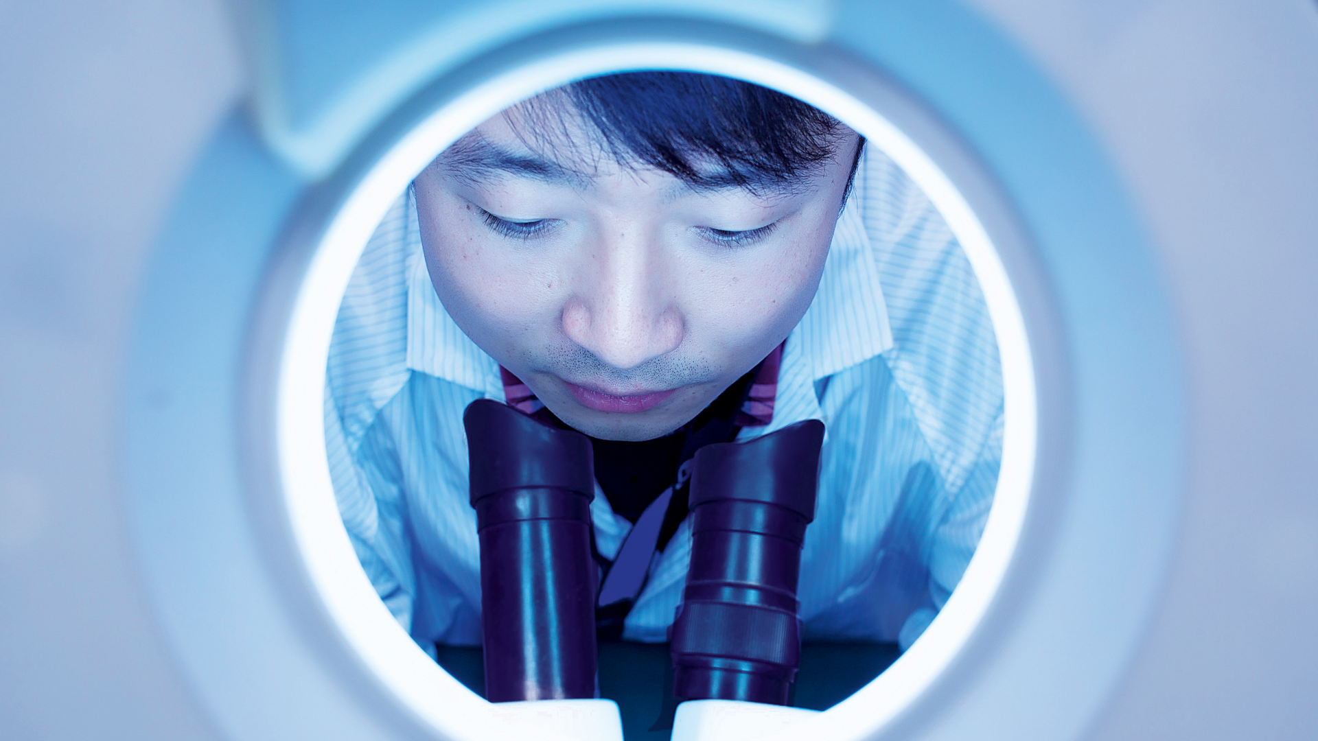 Asian employee looking into a microscope