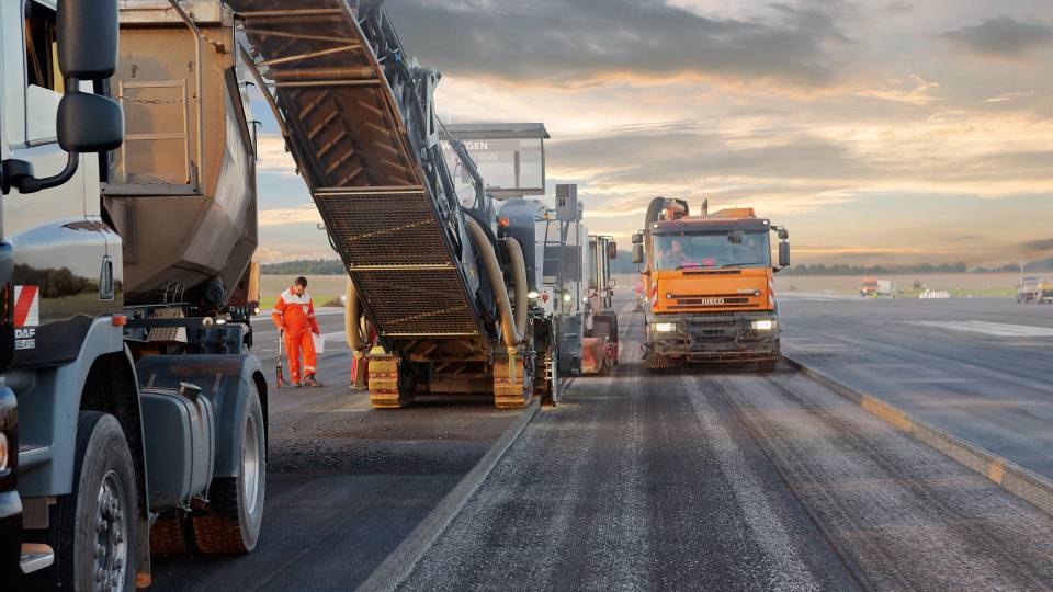 Eine WIRTGEN Fräse mit Förderband auf einer Baustelle